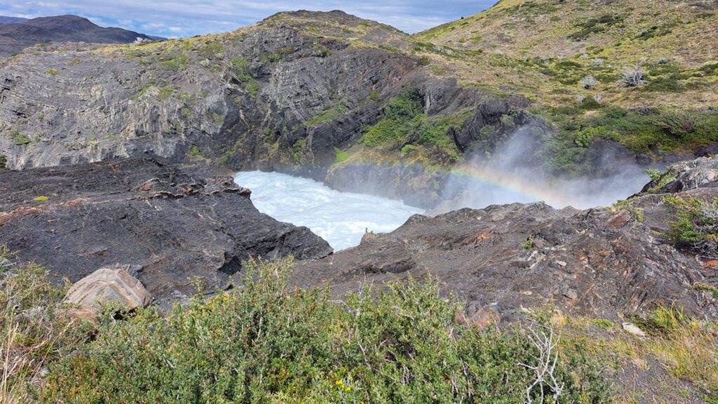 Vibrant waterfall with a rainbow in Magalhães, Chilean wilderness.