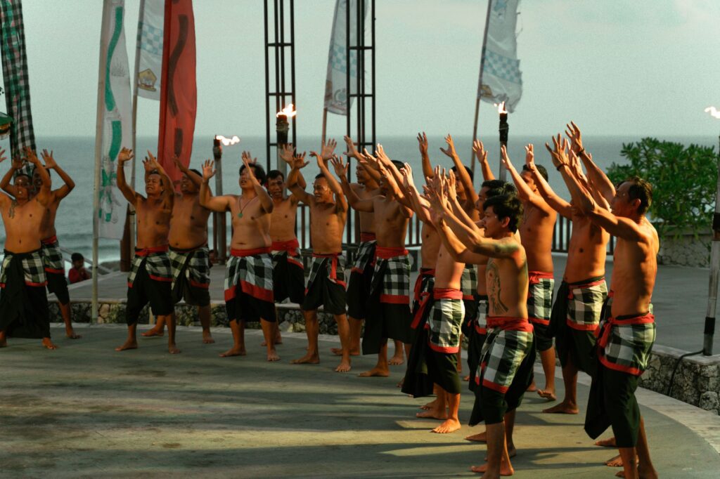 Traditional Balinese Kecak dance performed outdoors with scenic ocean backdrop.