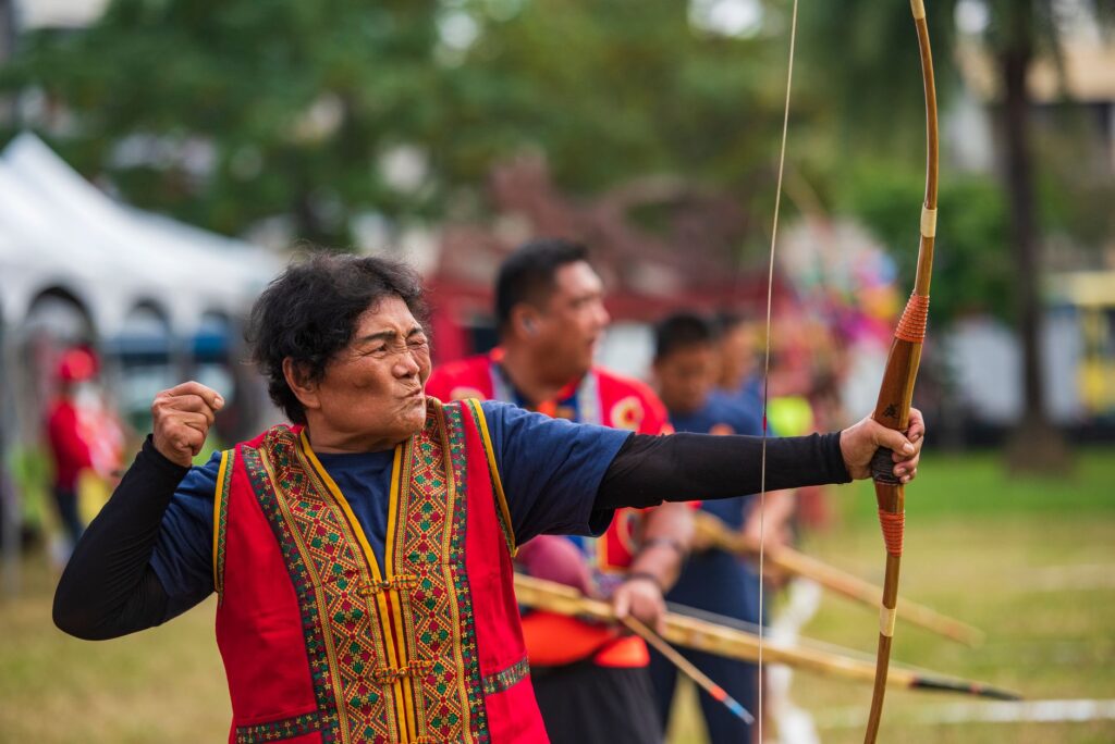 Senior woman participates in traditional archery event in Taiwan, showcasing cultural heritage.