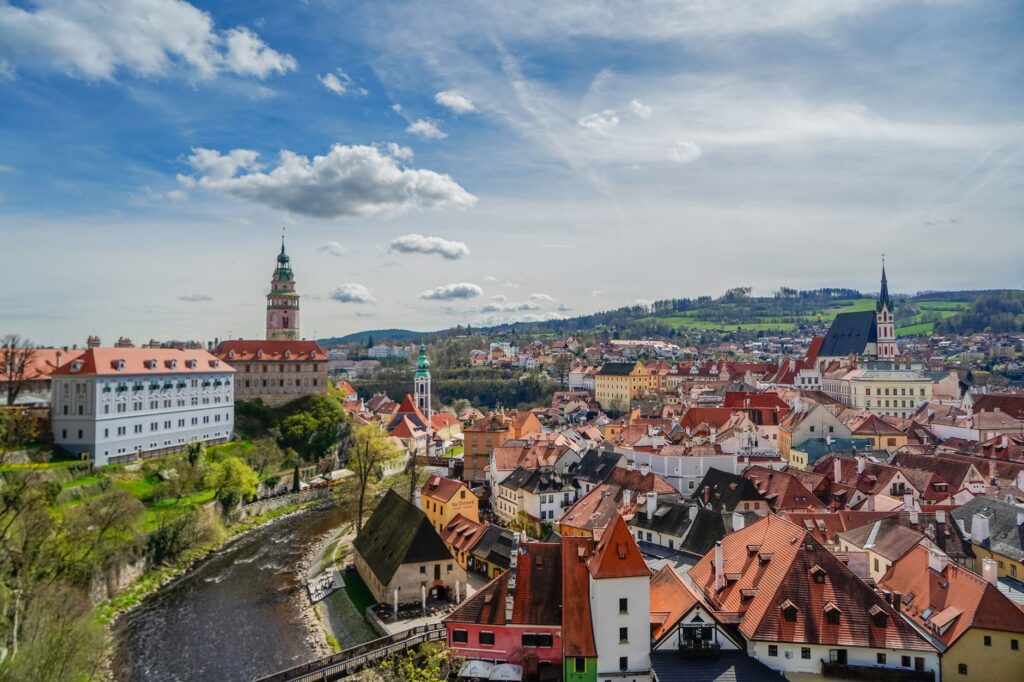 Aerial view of Cesky Krumlov with historic buildings and Vltava River under a blue sky.