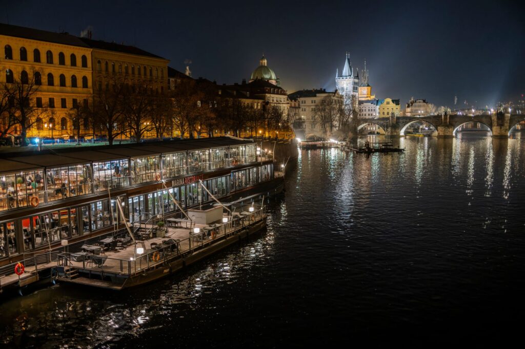 Night view of Prague's illuminated architecture and serene Vltava River reflections create a captivating scene.