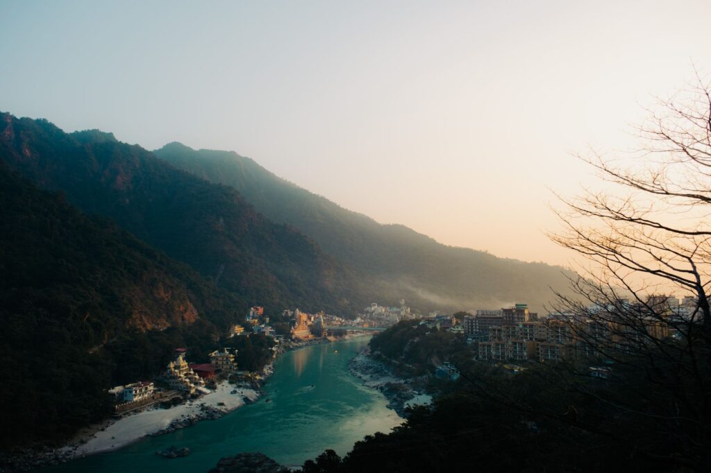 A beautiful view of Rishikesh with mountains and river Ganges during sunset, offering a serene landscape.