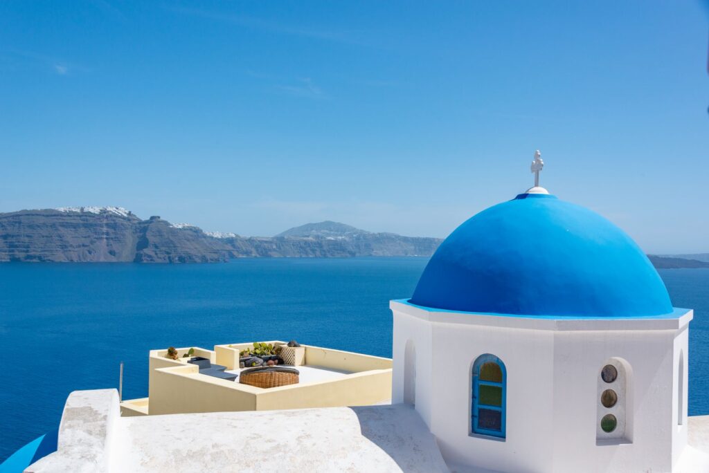 Iconic blue dome church in Santorini with a stunning view of the Aegean Sea.