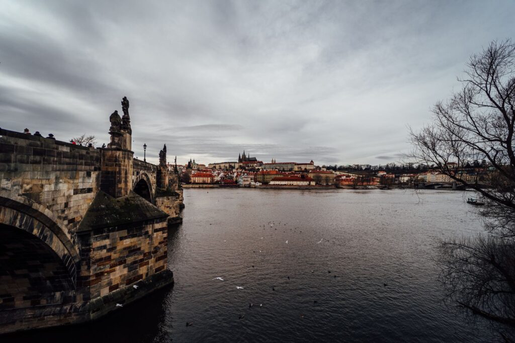 Stunning view of Charles Bridge and Prague Castle over the Vltava River on a cloudy day.