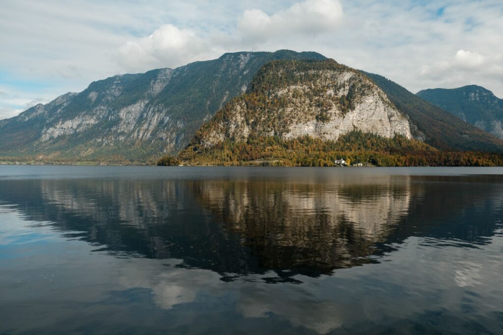 Beautiful landscape of Hallstatt with mountains reflected in the lake on a serene day.