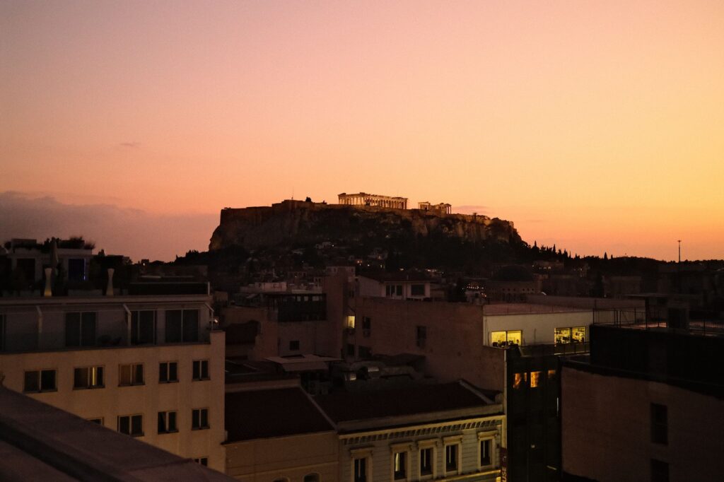 A stunning view of Athens featuring the Acropolis against a vibrant sunset sky.