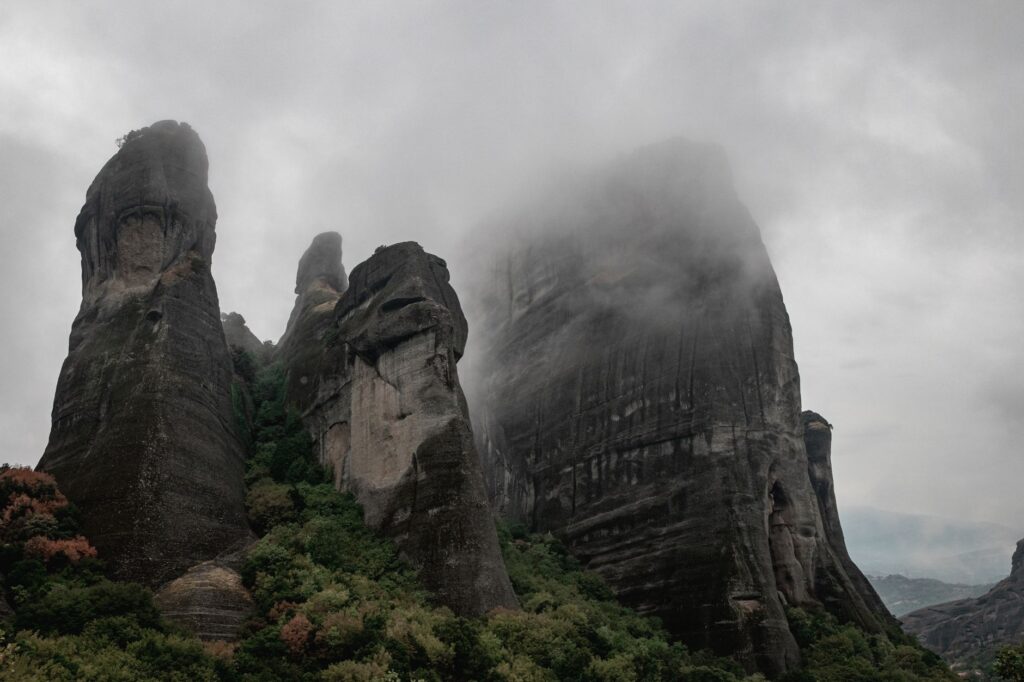 A captivating view of mist-shrouded rock formations in Meteora, Greece.