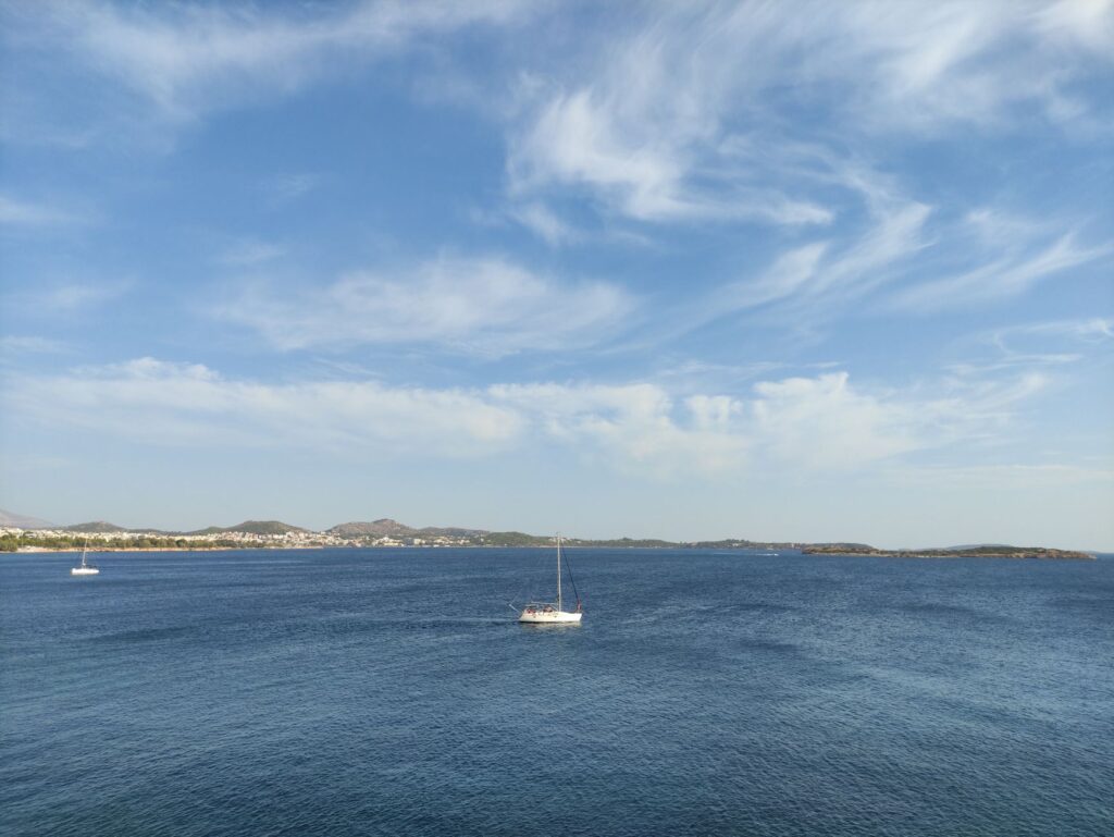 Aerial view of sailboats on the serene blue waters near Voula, Greece under a clear summer sky.