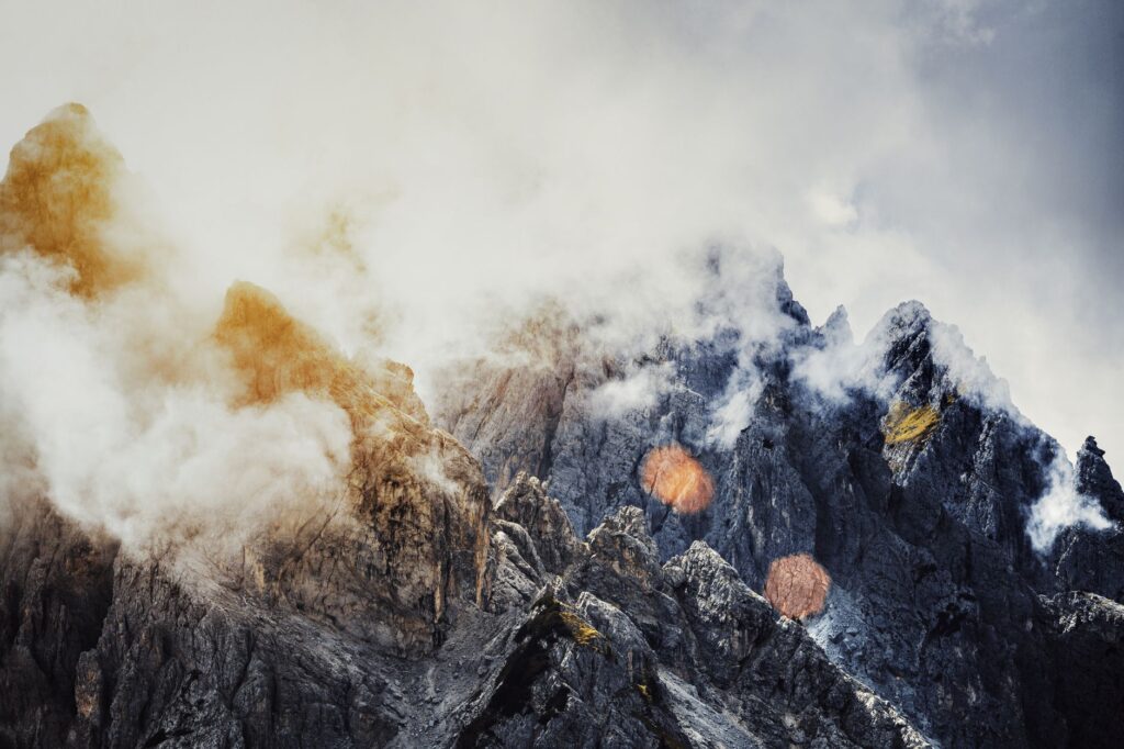 Explore dramatic rocky mountain peaks shrouded in clouds, creating a mystical landscape.
