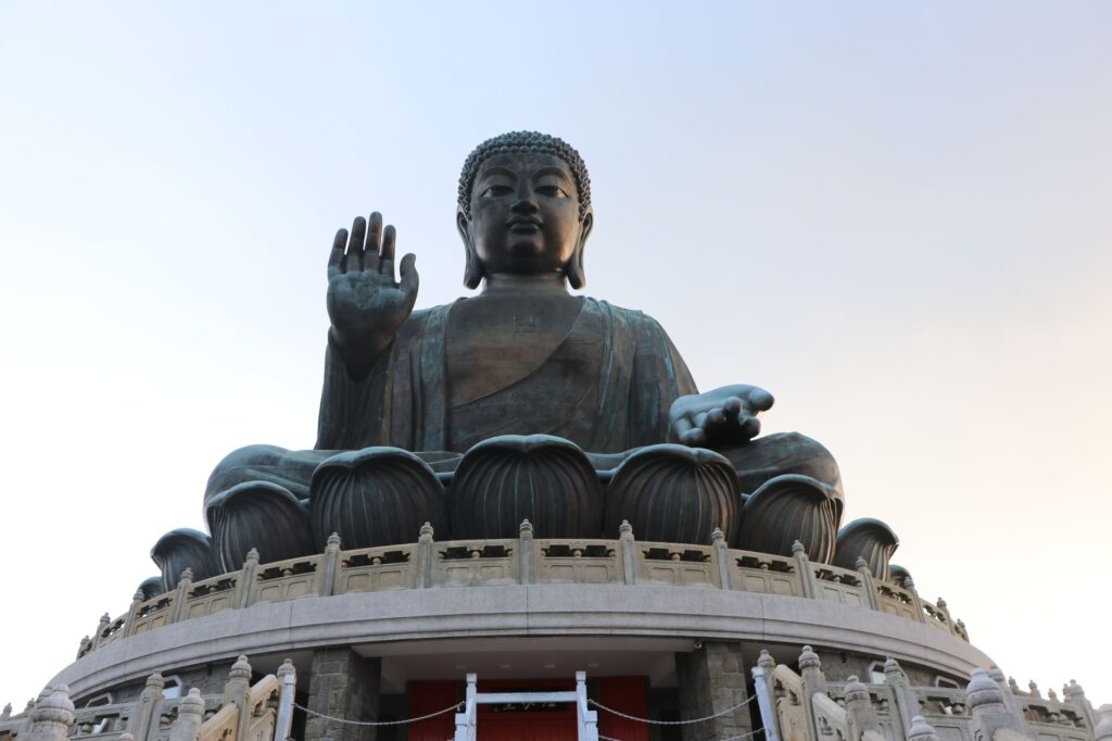 Low angle view of the iconic Tian Tan Buddha statue under a clear sky in Hong Kong.