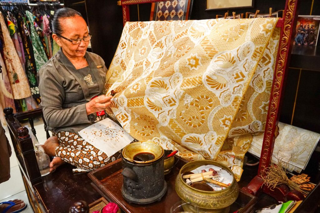Woman crafting traditional batik textile in Yogyakarta, Indonesia.