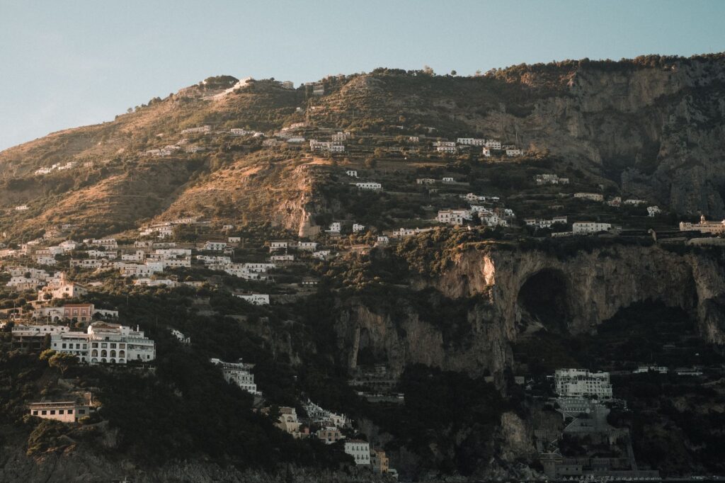 Dramatic aerial view of hillside villages on the rocky Amalfi Coast in Italy with stunning sunset light.