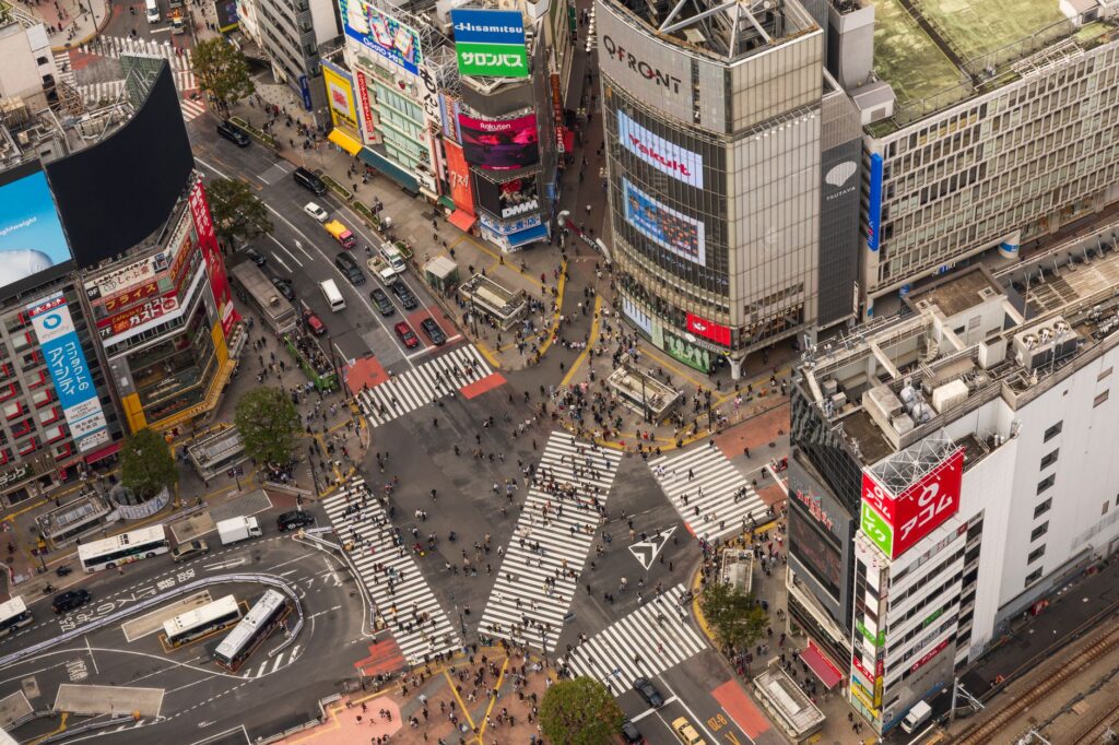 High-angle view of bustling Shibuya Crossing, Tokyo, with pedestrians and traffic.