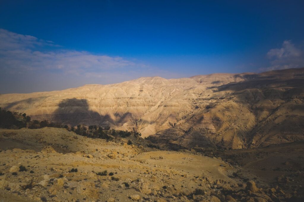 Breathtaking view of the arid Wadi Mujib canyon under a clear blue sky in Jordan.