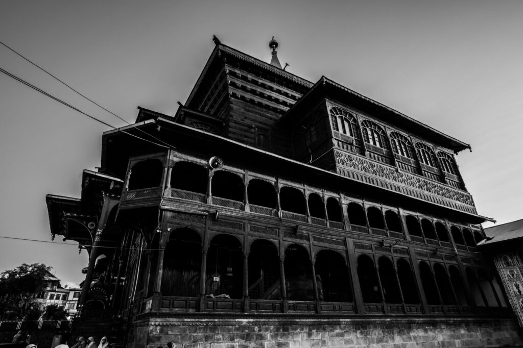 Striking low angle shot of Shah Hamdan Mosque showcasing its intricate facade in black and white.