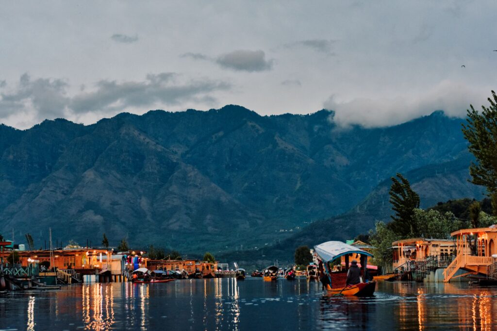 A peaceful view of Dal Lake in Srinagar with colorful boats against the backdrop of majestic mountains.