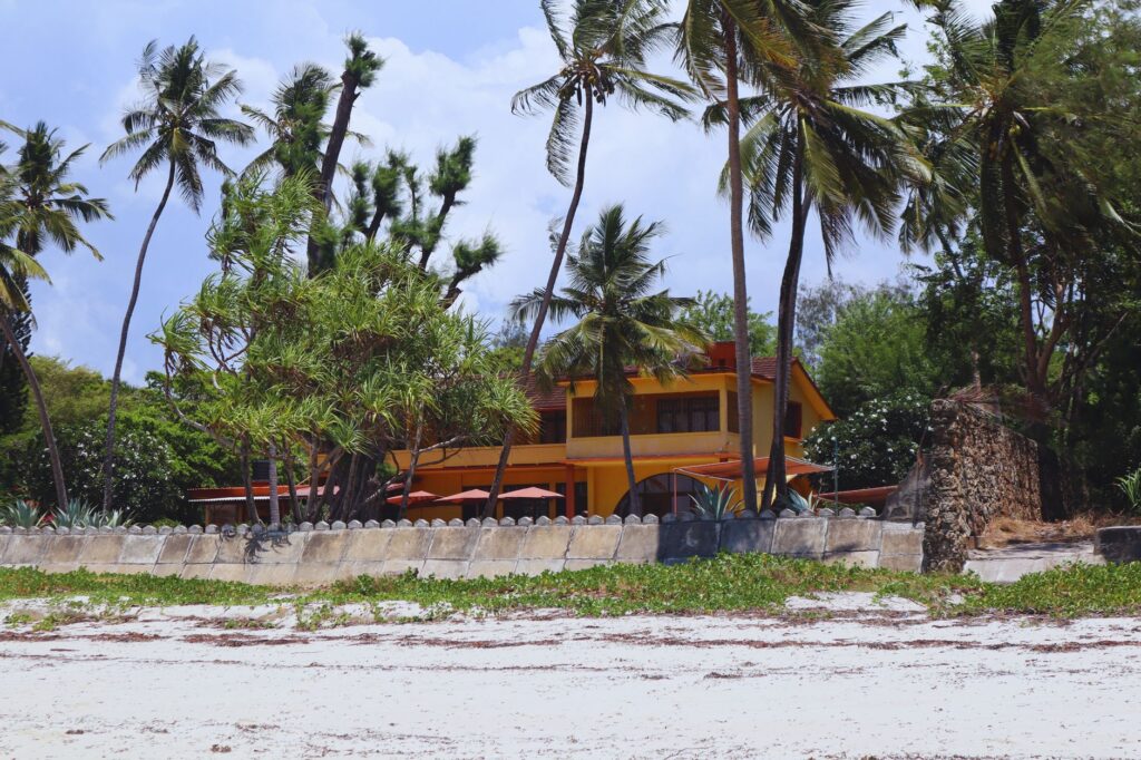 A serene beachfront house in Mombasa, Kenya, surrounded by palm trees and lush greenery.