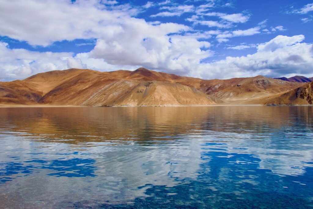 Stunning view of Pangong Tso Lake reflecting arid hills and blue sky. Perfect for travel inspiration.