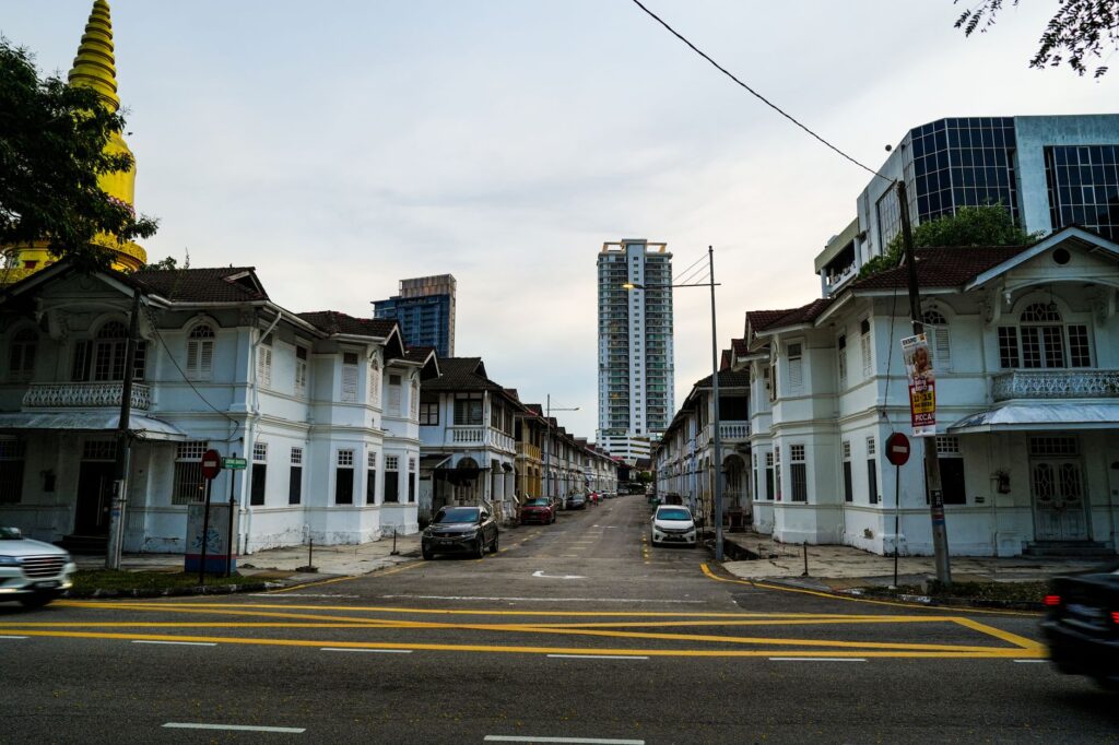 Scenic view of a Penang street with colonial architecture and modern buildings on a cloudy day.
