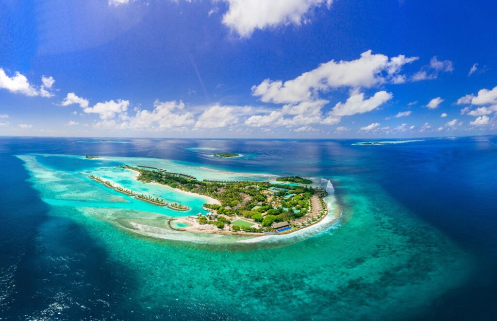 Stunning aerial view of a tropical island surrounded by turquoise waters in the Maldives.