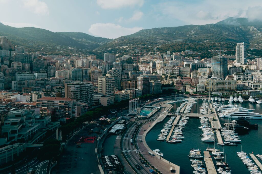 Stunning aerial view of Monaco cityscape with luxury yachts in the harbor under a sunny sky.
