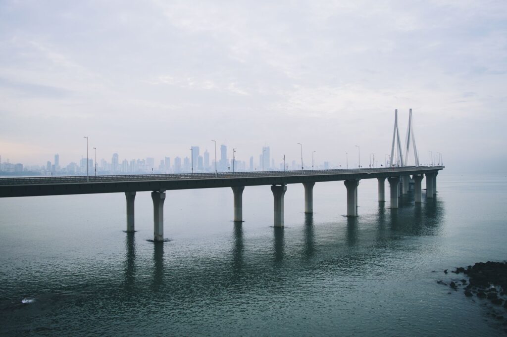 View of Bandra-Worli Sea Link with Mumbai's skyline under a cloudy sky.