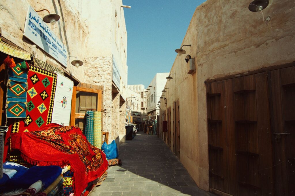 A vibrant alley in a Middle Eastern souq with colorful rugs and shops.