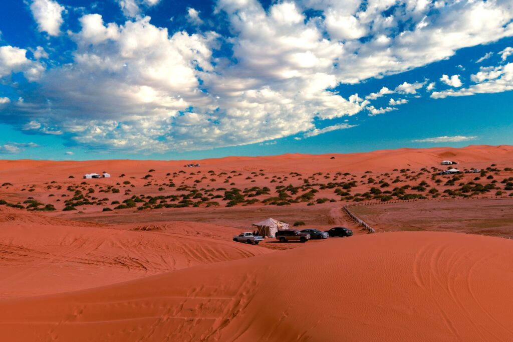 A stunning view of the desert in Shaqra, with cars and tents under a dramatic sky.