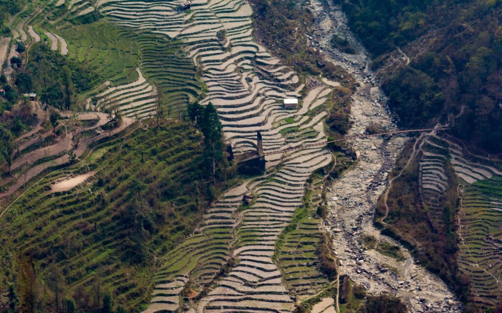 Aerial view of terraced fields and river in the Indian countryside, showcasing natural beauty and agriculture.