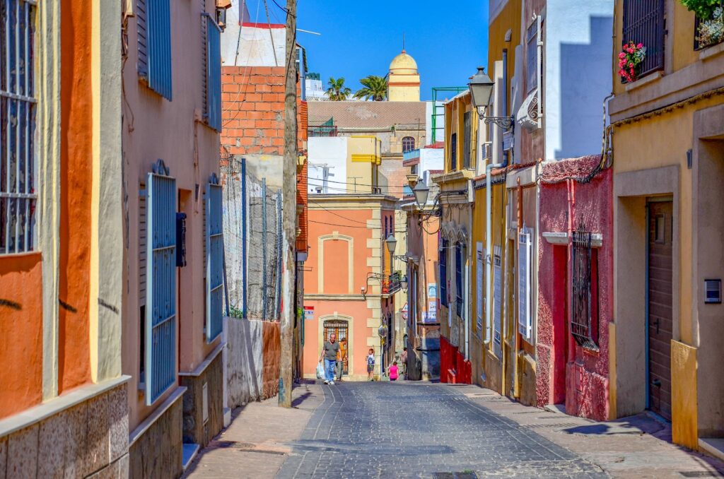 Charming sunlit street in Almería, Spain, with vibrant buildings and architectural charm.