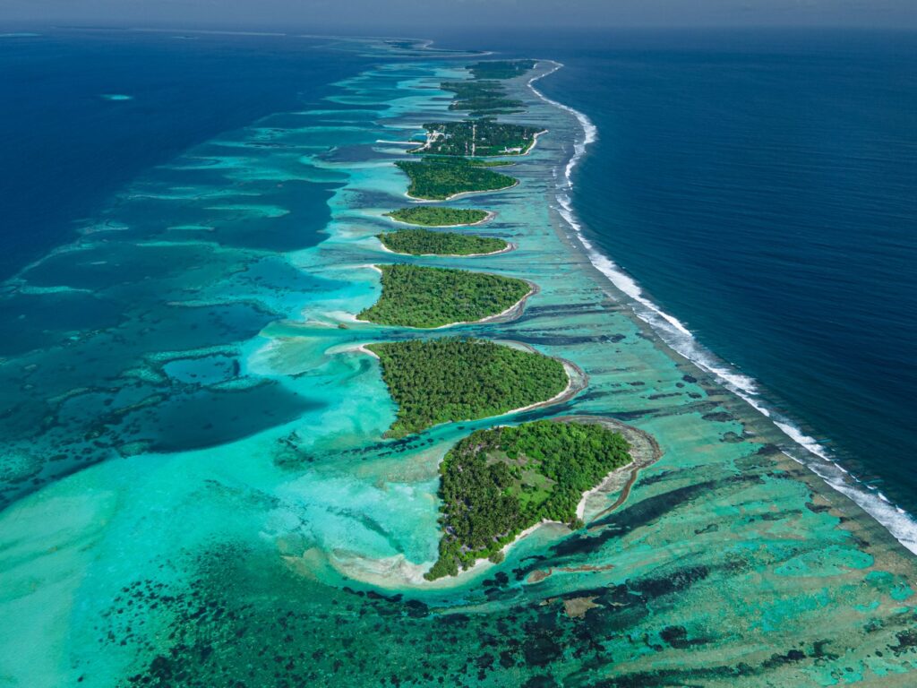 A breathtaking aerial shot of a Maldives atoll with vibrant blue waters and green islands.