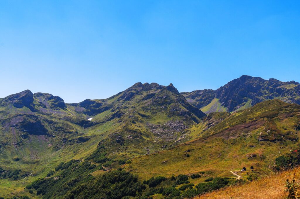 Majestic mountains with lush greenery under clear blue sky, perfect for nature enthusiasts.