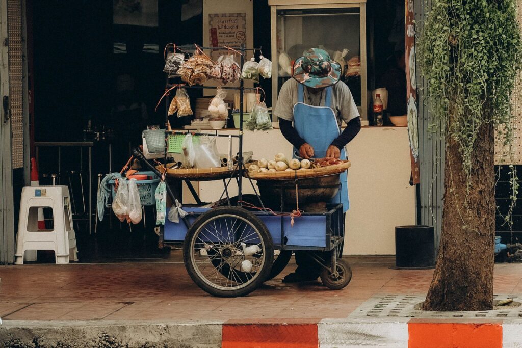 Street vendor in Bangkok selling fruits from a cart on a bustling street.