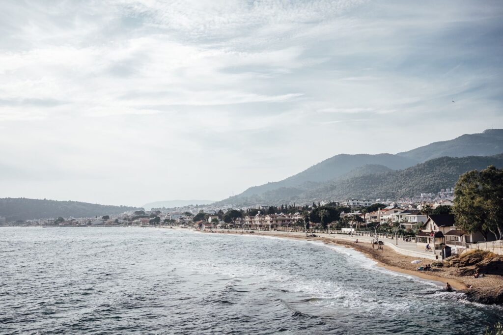 Scenic coastal view of Ozdere in Izmir, Turkey featuring beach, sea, and hills.