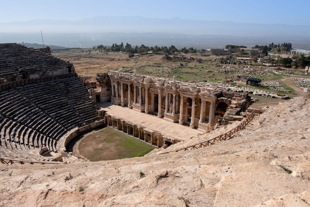 Aerial view of a historic Roman amphitheater in a vast outdoor landscape.