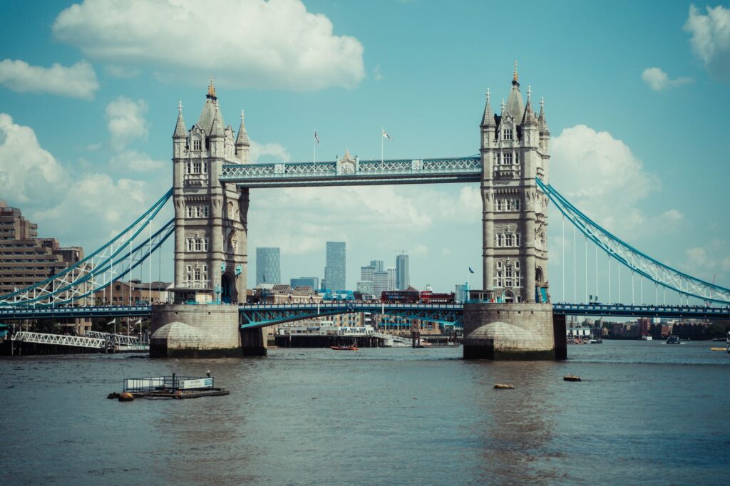 Iconic Tower Bridge in London stands tall over the River Thames under a bright blue sky.