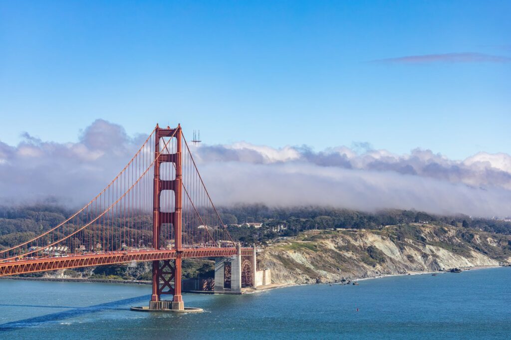 A stunning aerial view of the iconic Golden Gate Bridge with clouds and a blue sky in San Francisco.