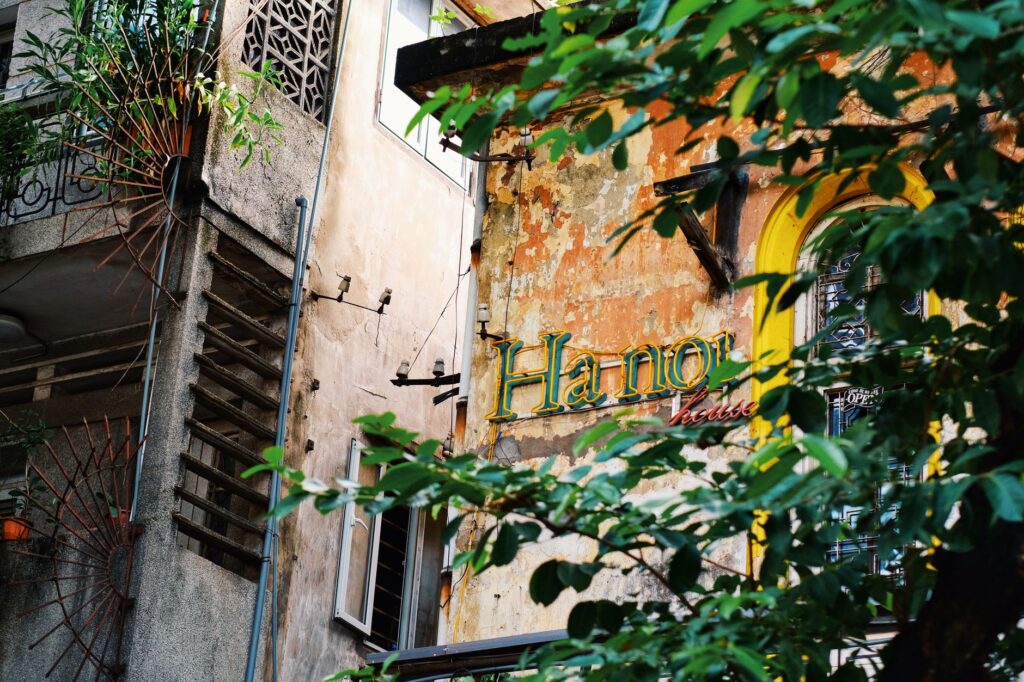 Rustic urban building in Hanoi with lush greenery and distinct signage.