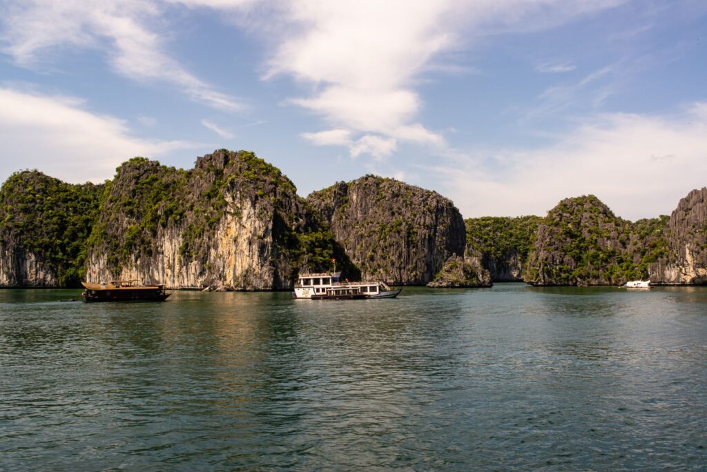Stunning limestone karsts and boats in Ha Long Bay, Vietnam, under a clear sky.
