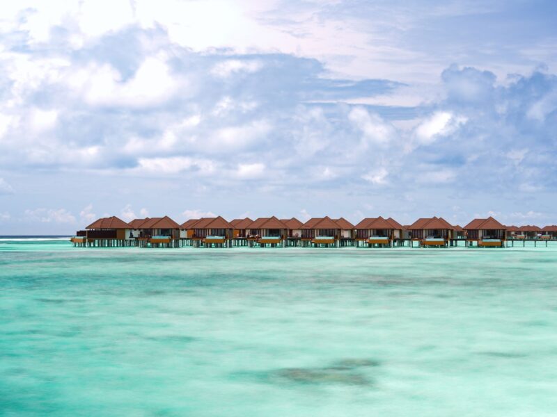 Idyllic overwater bungalows in turquoise sea with dramatic skies.