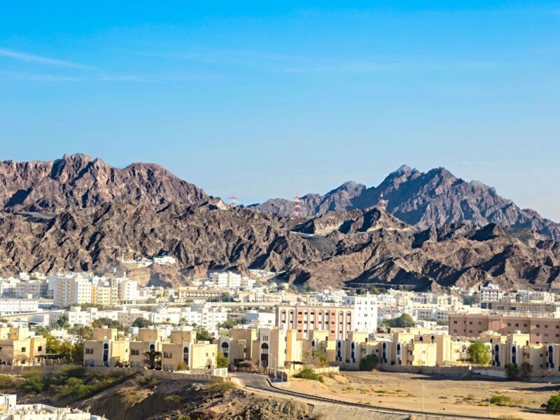 A vibrant city nestled against rugged mountains under a clear blue sky.