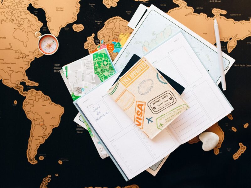 A flat lay of travel planning items on a map, featuring a compass, notebook, and guide for wanderlust enthusiasts.